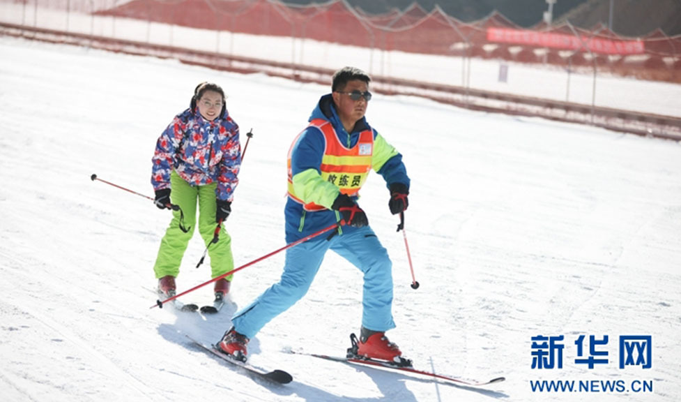 一名教练在训练基地指导滑雪爱好者滑雪
